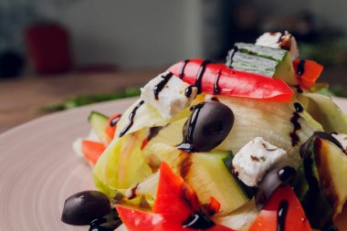 Ahşap masa zemininde çatallı cam tabakta Yunan salatası.