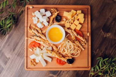 Şarap ve atıştırmalık seti. Çeşitli peynir, zeytin, prosciutto, kızarmış baget dilimleri, tahta tahtada üzümler ve gri mermer arka planda kırmızı şarap, seçici odak, kare mahsul.