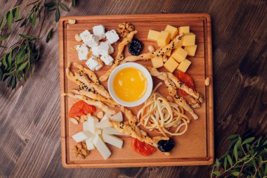 Şarap ve atıştırmalık seti. Çeşitli peynir, zeytin, prosciutto, kızarmış baget dilimleri, tahta tahtada üzümler ve gri mermer arka planda kırmızı şarap, seçici odak, kare mahsul.