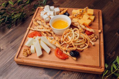 Şarap ve atıştırmalık seti. Çeşitli peynir, zeytin, prosciutto, kızarmış baget dilimleri, tahta tahtada üzümler ve gri mermer arka planda kırmızı şarap, seçici odak, kare mahsul.