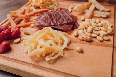 Şarap ve atıştırmalık seti. Çeşitli peynir, zeytin, prosciutto, kızarmış baget dilimleri, tahta tahtada üzümler ve gri mermer arka planda kırmızı şarap, seçici odak, kare mahsul.