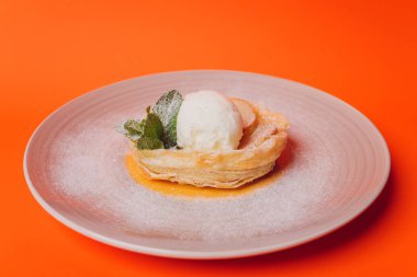 Turuncu arka planda dondurmalı tatlı pasta izole..