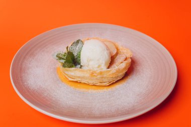 Turuncu arka planda dondurmalı tatlı pasta izole..