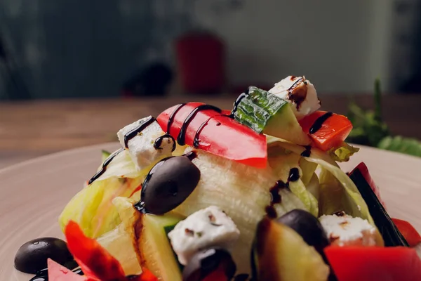 Salada grega em prato de vidro com garfo em fundo de mesa de madeira. — Fotografia de Stock