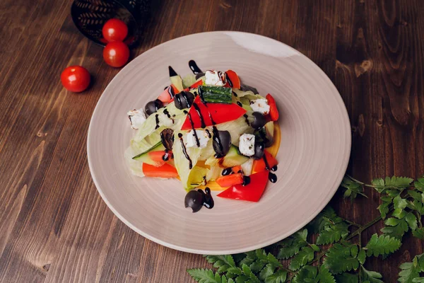 나무로 된 탁자 배경에 포크를 얹은 유리 접시에 놓인 그리스 샐러드. — 스톡 사진