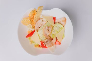 Tavuklu Sezar salatası ve beyaz arka planda yeşiller..