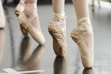 Gösteriden önce terliklerini bağlıyordu. Beyaz etekli genç balerin, otururken terliklerini bağlıyor..