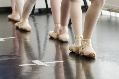 Gösteriden önce terliklerini bağlıyordu. Beyaz etekli genç balerin, otururken terliklerini bağlıyor..