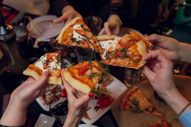 Arkadaşlar tabaktan lezzetli pizzalar alıyor, yakın plan..