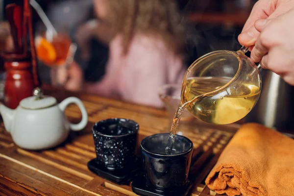 Üç kadın arkadaş piknik yapıyor, demir bardaklardan sıcak çay içiyor, gün batımında sahilde oturuyor..