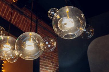 Tahta kahverengi bir duvarın yanında bir sürü yuvarlak lamba var. İç kısımda yuvarlak ışıklar var. Tasarım için arka plan. Dekoratif ampuller.