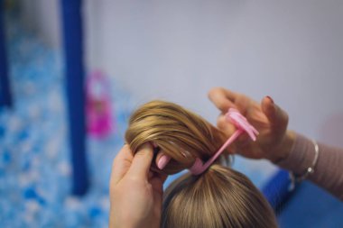 Üst düzey seçici bakış, kızının saçına örgü ören annenin ellerine odaklanıyor..