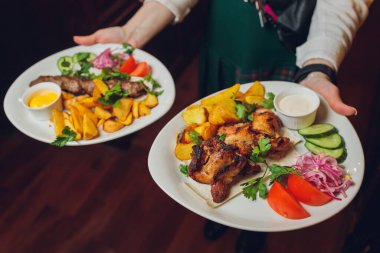 Restoran garsonunun ellerinde tavada sebzeli sıcak et pişirdim..