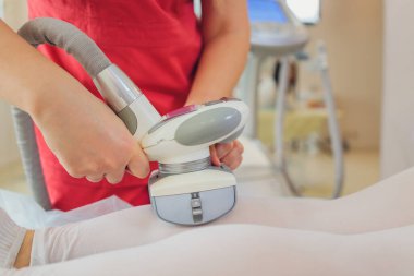 Beyaz takım elbiseli bir kadın spa salonunda selülit karşıtı masaj yaptırıyor. Klinikte LPG ve vücut şekillendirme tedavisi.