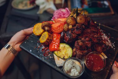 Izgara sebzeli biftek ve servis masasında baharat..