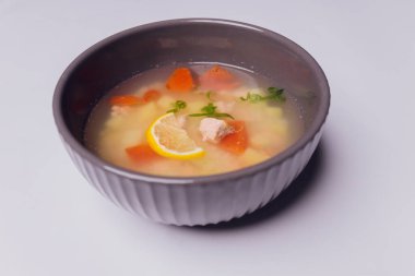 Kasede somon ve gri dokulu arka planda çavdar ekmeği dilimleri olan kremalı çorba, seçici bir odak noktası..