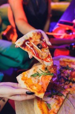 Yemek yemek. İnsanların ellerinin biberli pizzadan dilimler aldığı yakın çekim. Arkadaş gurubu pizzayı paylaşıyor. Fast food, arkadaşlık, eğlence, yaşam tarzı..