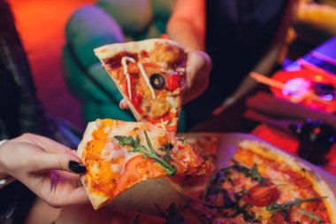 Yemek yemek. İnsanların ellerinin biberli pizzadan dilimler aldığı yakın çekim. Arkadaş gurubu pizzayı paylaşıyor. Fast food, arkadaşlık, eğlence, yaşam tarzı..