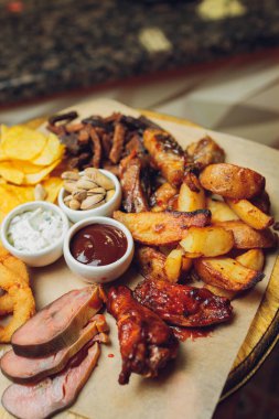 Tahtaya konmuş et. Kızarmış tavuk kanadı, domuz kaburgası, ızgara sebze, patates kızartması. Soslu bira aperatifi. arkaplan resmi.