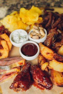 Tahtaya konmuş et. Kızarmış tavuk kanadı, domuz kaburgası, ızgara sebze, patates kızartması. Soslu bira aperatifi. arkaplan resmi.