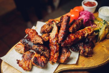 Tahtaya konmuş et. Kızarmış tavuk kanadı, domuz kaburgası, ızgara sebze, patates kızartması. Soslu bira aperatifi. arkaplan resmi.