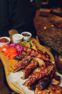 Tahtaya konmuş et. Kızarmış tavuk kanadı, domuz kaburgası, ızgara sebze, patates kızartması. Soslu bira aperatifi. arkaplan resmi.