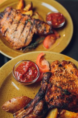 Masada ızgara kaburga bifteği ve sarı patates dilimleri ve tabağın üstündeki tabakta yağ ile fotokopi alanı..