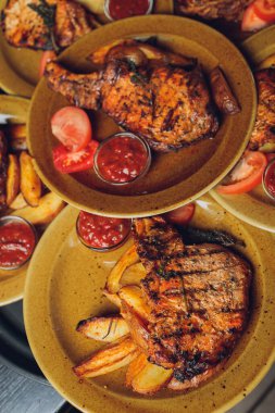 Masada ızgara kaburga bifteği ve sarı patates dilimleri ve tabağın üstündeki tabakta yağ ile fotokopi alanı..