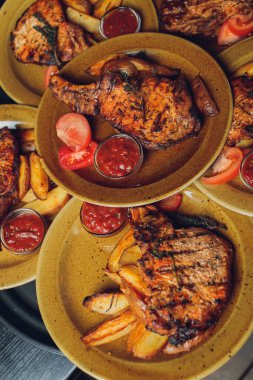 Masada ızgara kaburga bifteği ve sarı patates dilimleri ve tabağın üstündeki tabakta yağ ile fotokopi alanı..