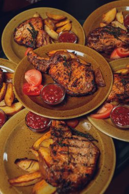 Masada ızgara kaburga bifteği ve sarı patates dilimleri ve tabağın üstündeki tabakta yağ ile fotokopi alanı..