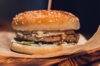 Burger Piled High 'ın Kapanışı Tam Taneli Sanatsal Çörek Üzerine Taze Toppingler Koyu Arkaplan ve Boşluk Kopyalama Arkaplanı Taşralı Tahta Yüzey.