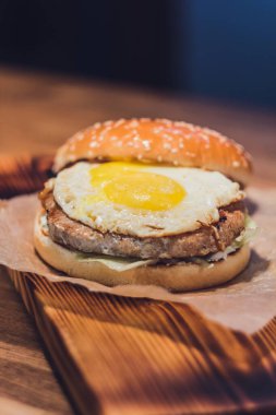 Burger Piled High 'ın Kapanışı Tam Taneli Sanatsal Çörek Üzerine Taze Toppingler Koyu Arkaplan ve Boşluk Kopyalama Arkaplanı Taşralı Tahta Yüzey.
