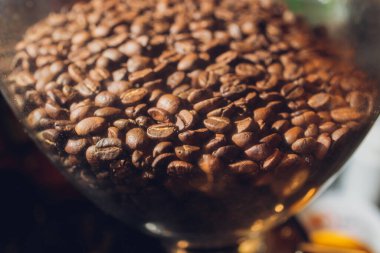 Kahve tanecikli cam bankası siyah arka plandaki bir masada..