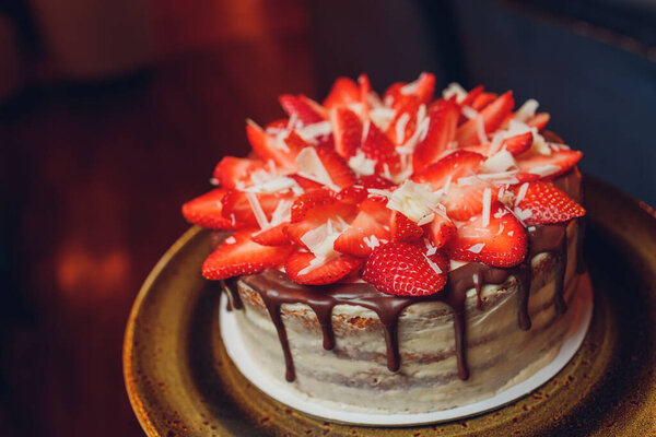 Сладкий торт с клубникой на тарелке на сером деревянном фоне.