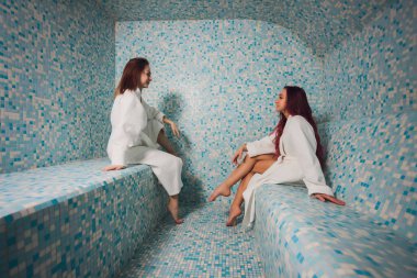 Mozaiğin güzel bir hamamında beyaz köpük içinde genç bir kadın..