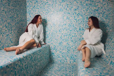 Mozaiğin güzel bir hamamında beyaz köpük içinde genç bir kadın..