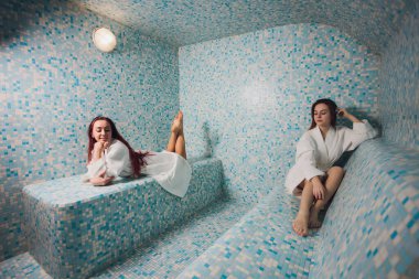 Mozaiğin güzel bir hamamında beyaz köpük içinde genç bir kadın..