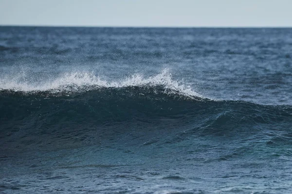 Pequenas ondas marinhas se quebram contra as pedras da costa. Um dia ensolarado brilhante e espuma branca das ondas. Geleiras de fusão como impacto ambiental da poluição atmosférica. — Fotografia de Stock