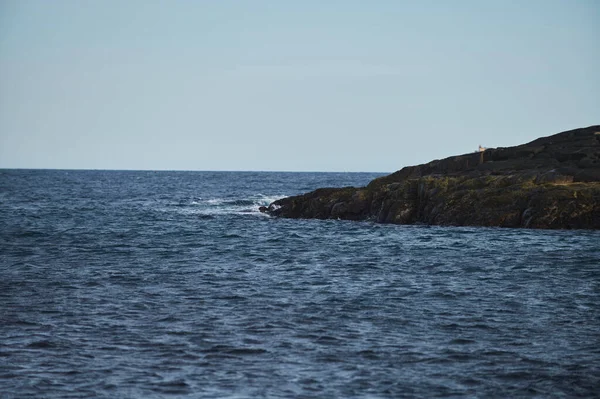 Small sea waves break against the stones of the shore. A bright sunny day and white foam of the waves. Melting glaciers as an environmental impact of air pollution.