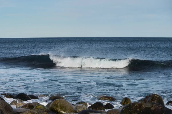 Μικρά κύματα της θάλασσας σπάνε στις πέτρες της ακτής. Μια φωτεινή ηλιόλουστη μέρα και λευκό αφρό των κυμάτων. Οι παγετώνες τήξης ως περιβαλλοντικές επιπτώσεις της ατμοσφαιρικής ρύπανσης. — Φωτογραφία Αρχείου