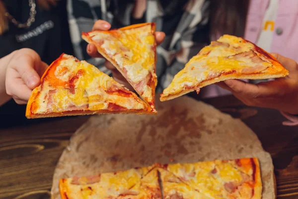 Cerca de la mano femenina sosteniendo, tomando rebanada, pedazo de amigos pizza sentados juntos en la cafetería, pasar gratis . — Foto de Stock