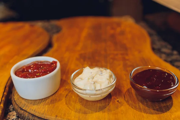 Set of different sauces on black wooden background. Top view. — Stock Photo, Image