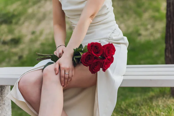 Primo piano di giovane donna mano che tiene fiori di rosa rossa su sfondo esterno. — Foto Stock