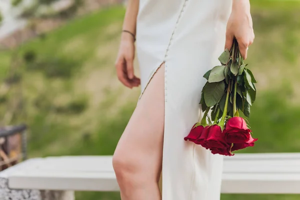 Close up of young woman hand holding red rose flowers on outdoor background. — Stock Photo, Image