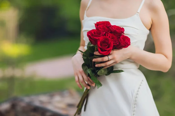 Крупным планом молодая женщина, держащая в руке красные розовые цветы на открытом фоне. — стоковое фото
