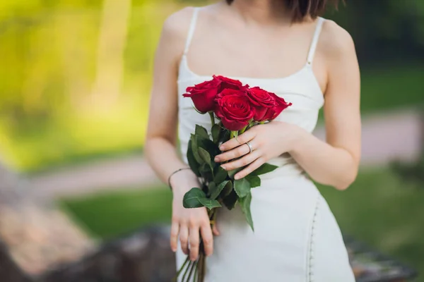 Zbliżenie młody kobieta ręka gospodarstwa czerwony róża kwiaty na zewnątrz tło. — Zdjęcie stockowe