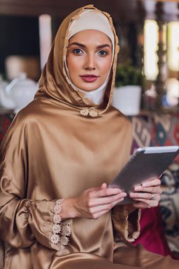 Dijital tablete bakan düşünceli Müslüman kadın..