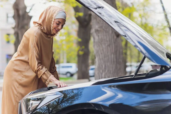 Mujer de Oriente Medio conduciendo un coche, mirando hacia el futuro. —  Fotos de Stock