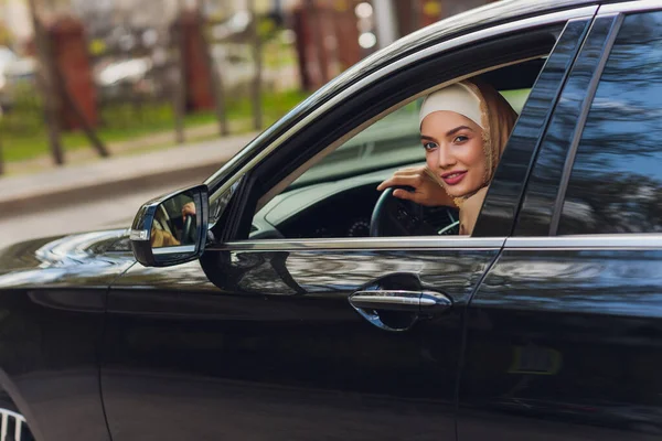 Mujer de Oriente Medio conduciendo un coche, mirando hacia el futuro. —  Fotos de Stock