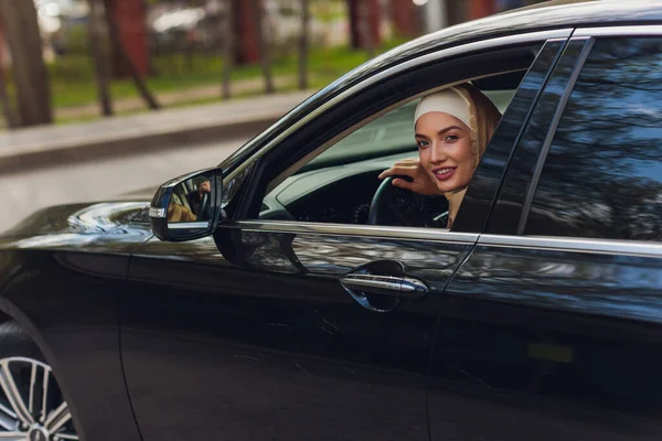 Mujer de Oriente Medio conduciendo un coche, mirando hacia el futuro. —  Fotos de Stock